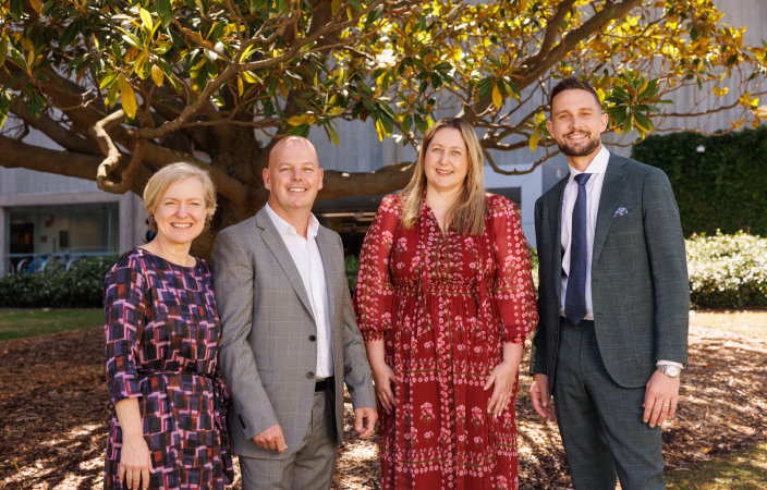 Four people standing together - two women, one man